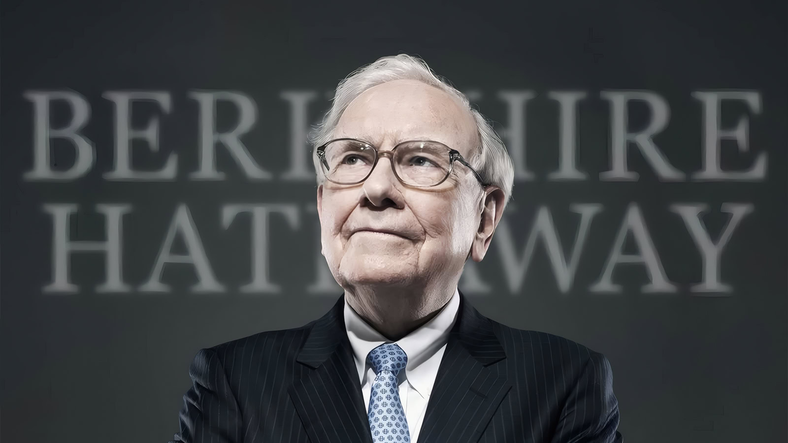 Ο Warren Buffett χαμογελαστός μπροστά από το λογότυπο της Berkshire
